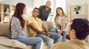 Image of members of a sober living home seated around a sofa - Should I Move to California for Sober Living - South Shores Recovery